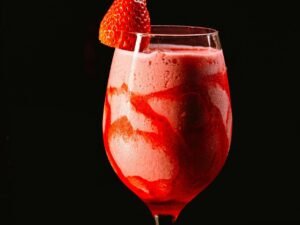Refreshing strawberry daiquiri in a wine glass with a fresh strawberry garnish on top, perfect for summer.