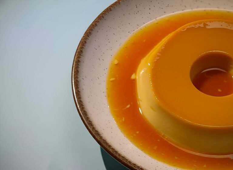 Delicious creamy caramel flan served on a ceramic plate with smooth texture in a gentle soft light.