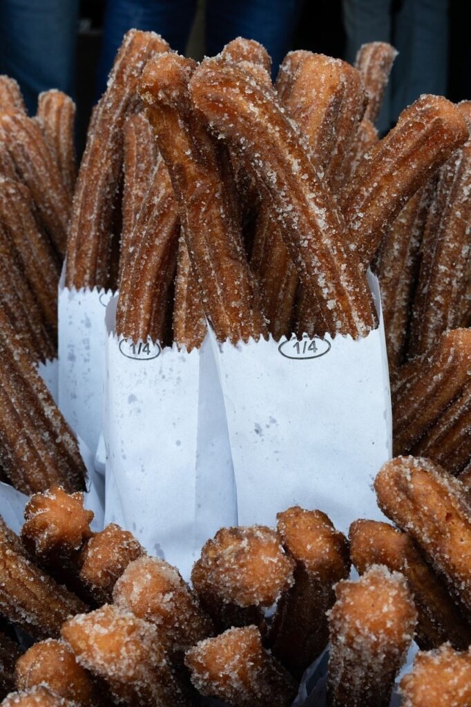 churros, mexican food, street food, dessert, sweet food, fried pastry, sugar coated, traditional food, snack, sugar, golden brown, crispy, sugar and cinnamon, wax paper, pastry, street market, popular food, food background, vertical photography