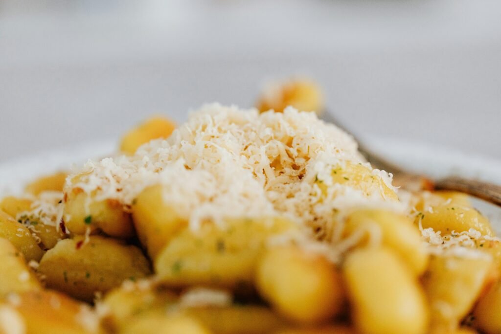 Close-up of gnocchi topped with freshly grated parmesan cheese, highlighting rich Italian flavors.