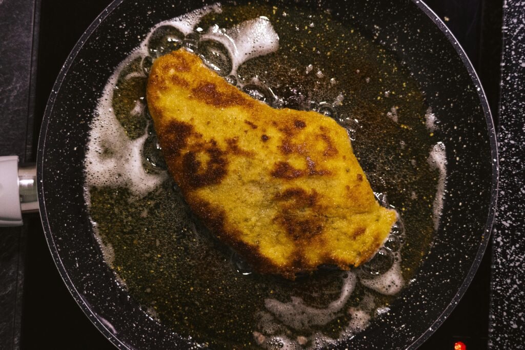 Golden schnitzel frying in a pan, capturing the essence of home-cooked comfort food.